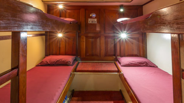 Solway Lass – Four (4) Share Cabin a bedroom with a bed and a chair in a room