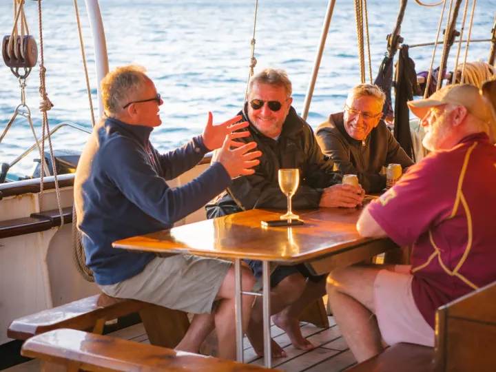 a group of people sitting at a table in front of a boat