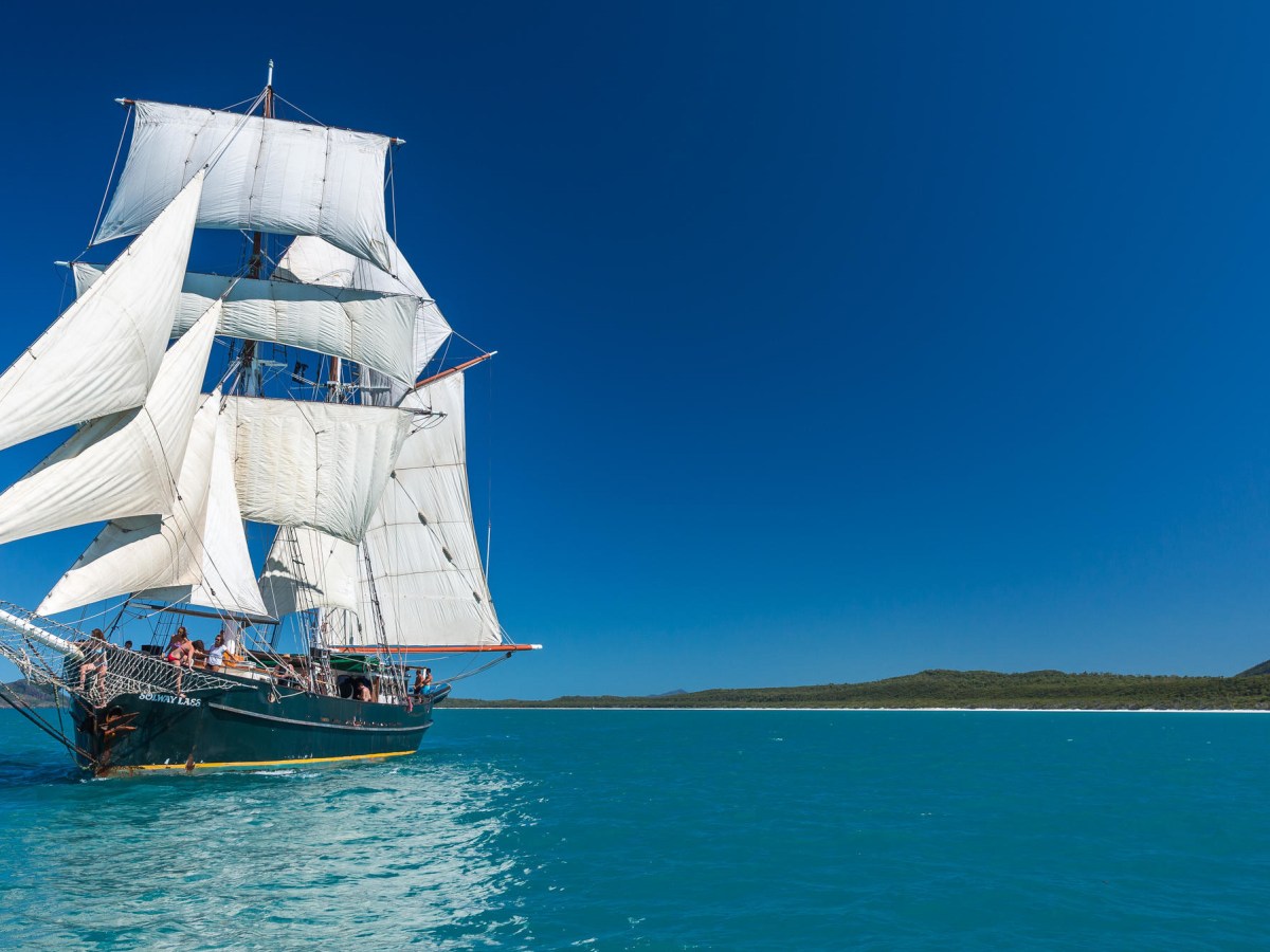 a blue and white boat sitting next to a body of water