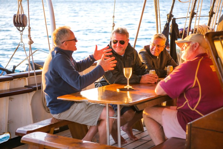 a group of people sitting at a table in front of a boat