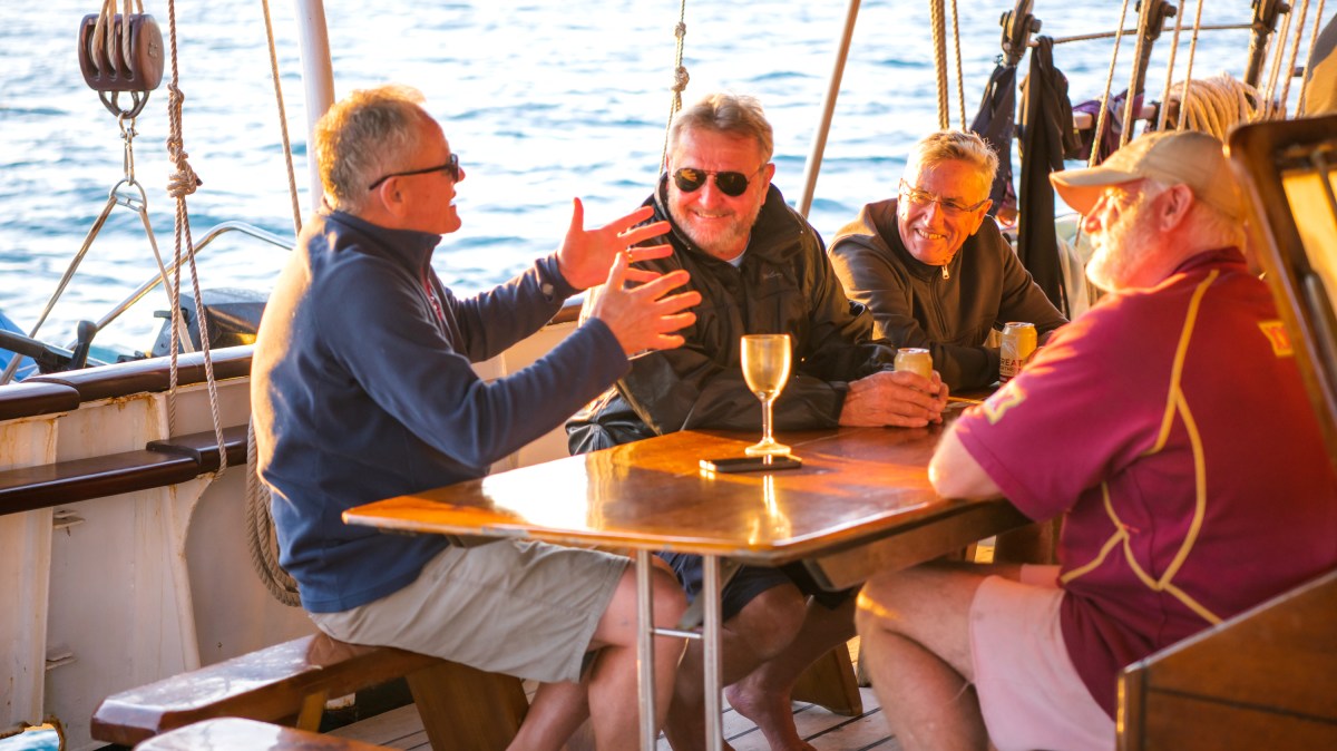 a group of people sitting at a table in front of a boat